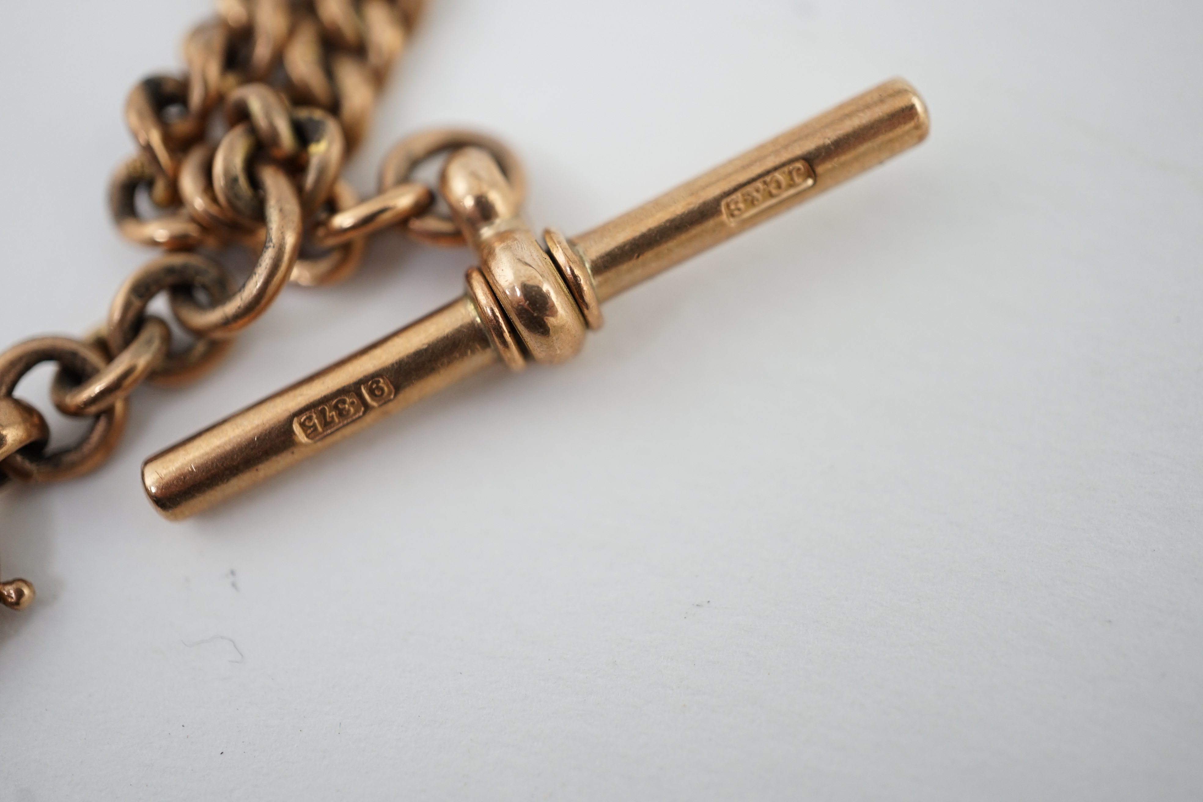 An Edwardian 9ct gold curb link albert, hung with a gold spinning Masonic charm